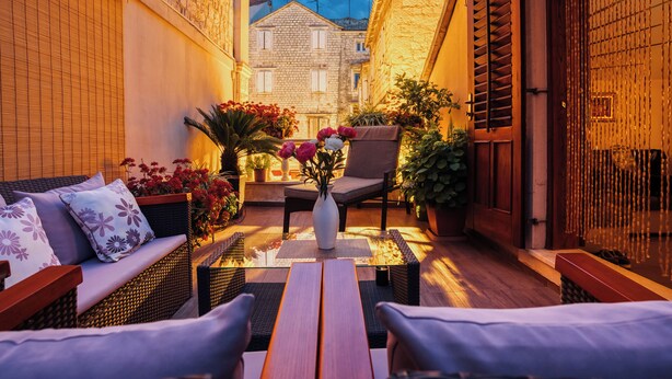 A cozy outdoor seating area with wicker furniture, a wooden table, and a vase with flowers. - Villa Trogir Stars (Trogir)