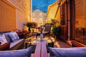 A cozy outdoor seating area with wicker furniture, a wooden table, and a vase with flowers. - Villa Trogir Stars (Trogir)