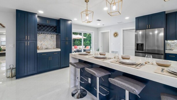 A modern kitchen with dark blue cabinets, a white countertop, and bar stools. - LUXURY  RETREAT 4-Bed in Palm Beach Shores - Singer Island - Walk to the Beach! (West Palm Beach)