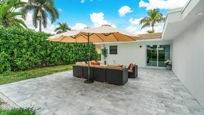An outdoor patio with a large wicker sofa set, a beige umbrella, and a tiled floor. - LUXURY  RETREAT 4-Bed in Palm Beach Shores - Singer Island - Walk to the Beach! (West Palm Beach)
