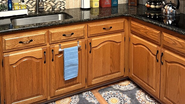 A kitchen with wooden cabinets, a black countertop, and a tiled backsplash.
