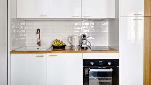 A modern kitchen with white cabinets, a stainless steel sink, a coffee maker, and an oven. - Charming Studio Near Place des Vosges Le Marais (Paris)