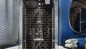A narrow shower area with a glass door, a white sink with a mirror, and a towel rack. - Charming Studio Near Place des Vosges Le Marais (Paris)