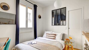 A neatly arranged bedroom with a bed, bedside table, and a small table with breakfast. - Charming Studio Near Place des Vosges Le Marais (Paris)