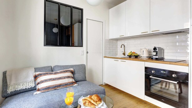 A compact kitchen with white cabinets, a built-in oven, and a coffee maker. - Charming Studio Near Place des Vosges Le Marais (Paris)