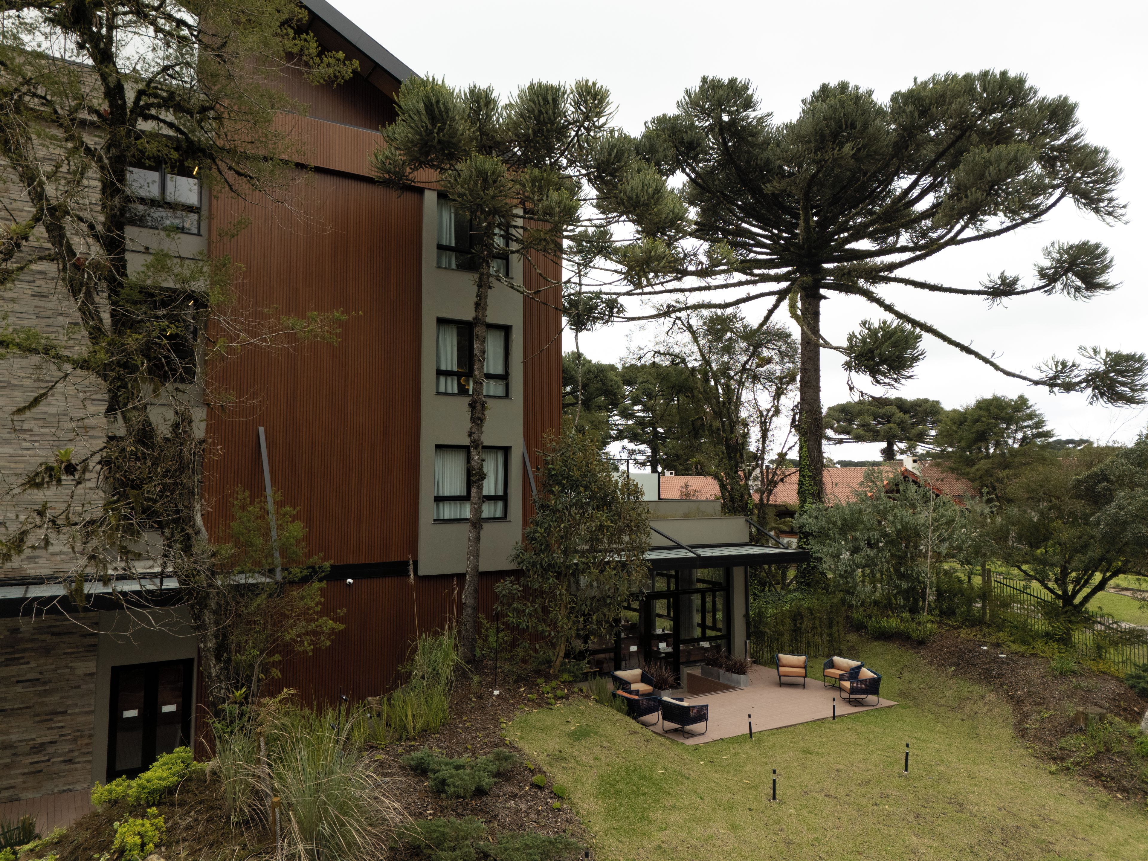 A modern building with a courtyard featuring outdoor seating and a large tree.