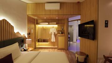 A hotel room with a bed, a bedside table, a TV, a wardrobe, and a bathroom visible through an open door.