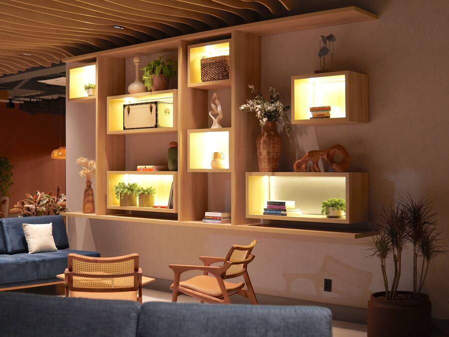 Ein modernes Wohnzimmer mit einem blauen Sofa, Holzstühlen und eingebauten Regalen mit Dekoration und Pflanzen.