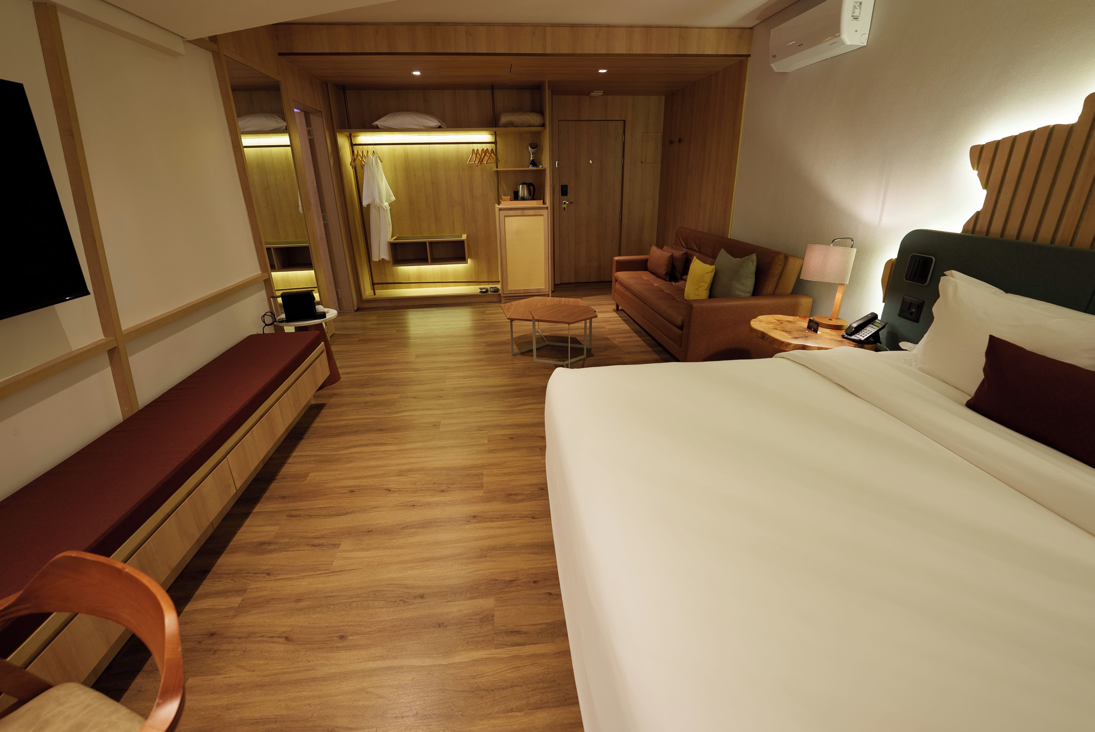 A hotel room with a bed, a desk, a sofa, and a kitchenette area.