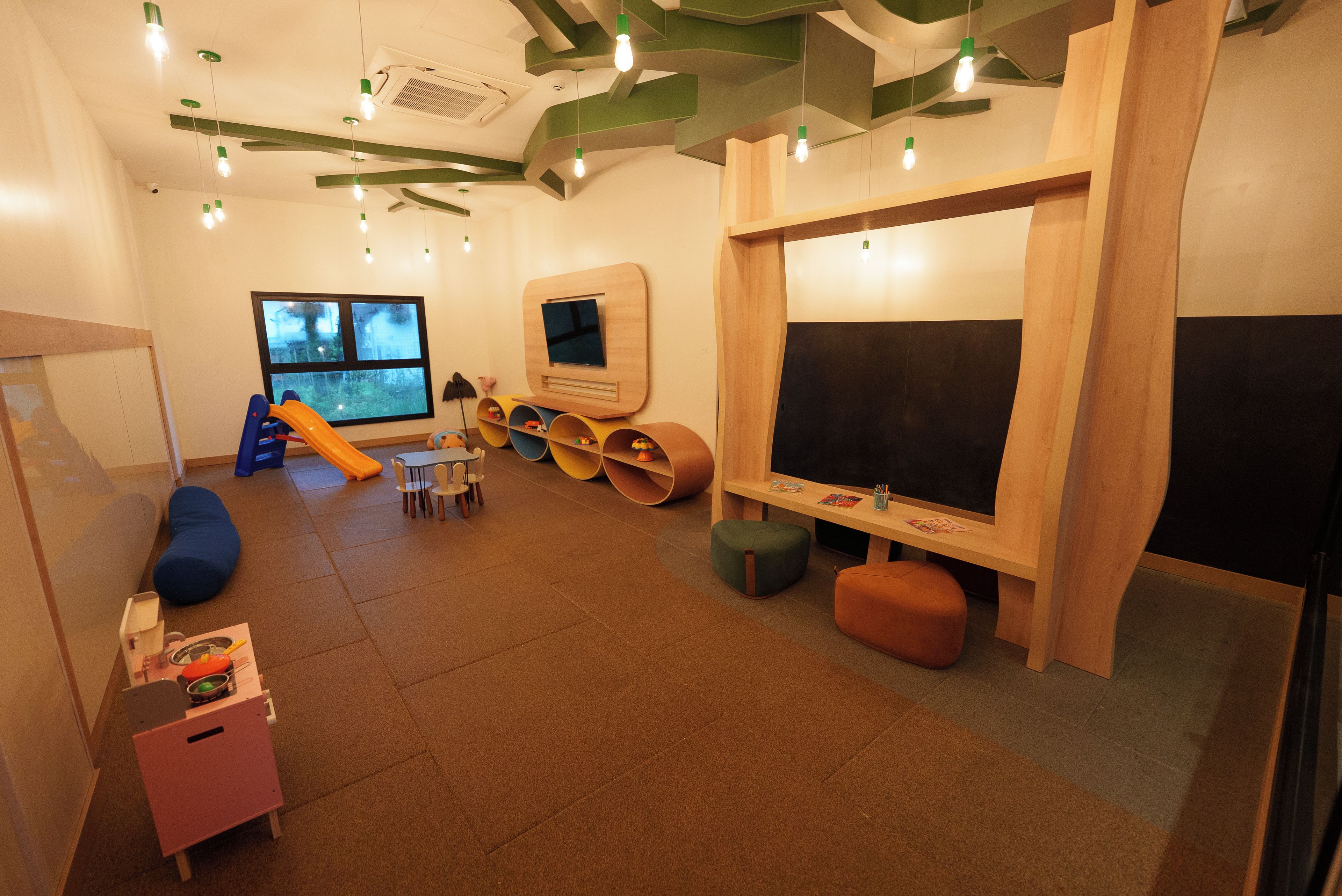A children's play area with a slide, seating, and a television.
