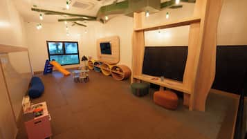 A children's play area with a slide, seating, and a television.