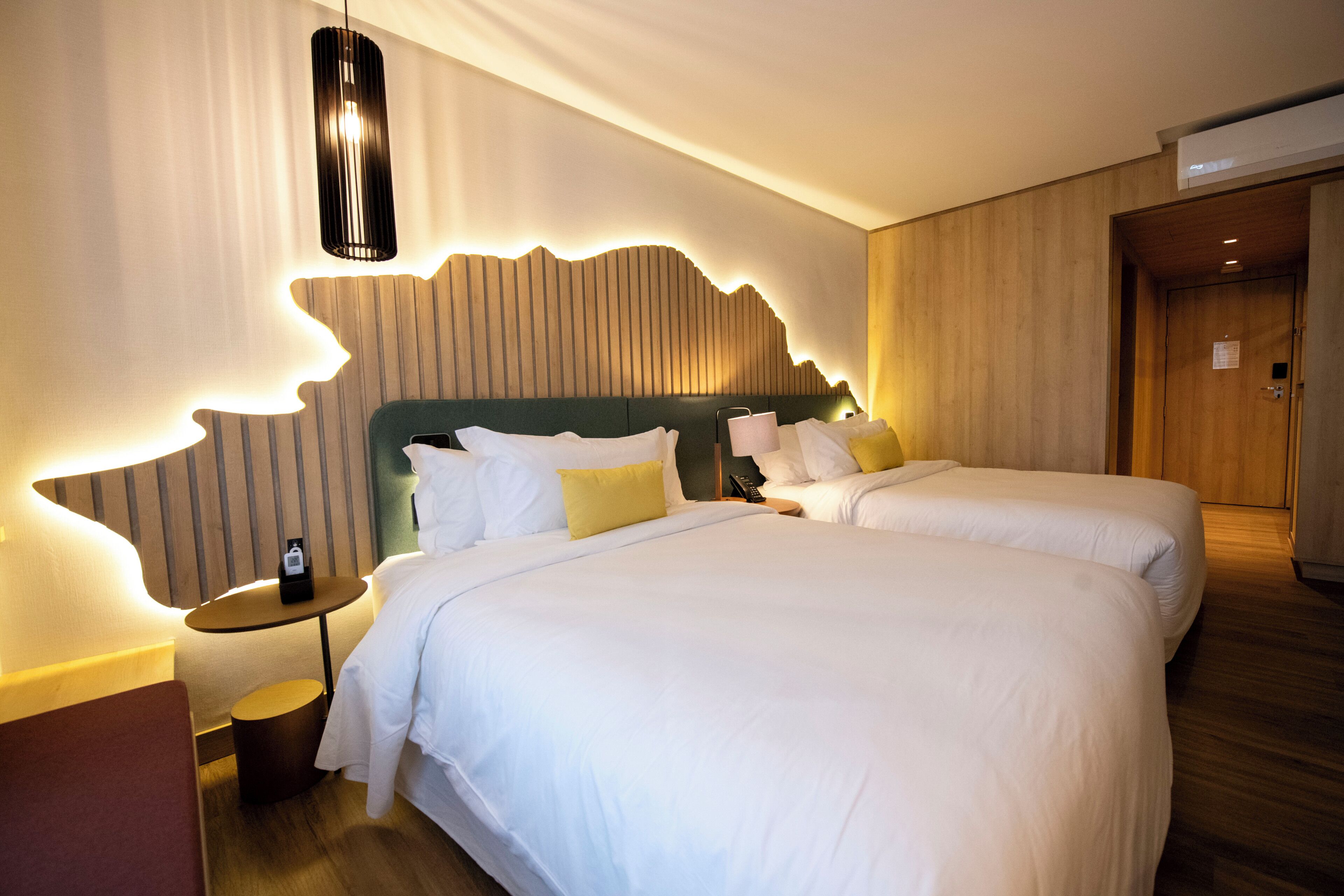 Habitación de hotel con dos camas, cabecero de madera, una mesita redonda y una mesita de noche con teléfono.