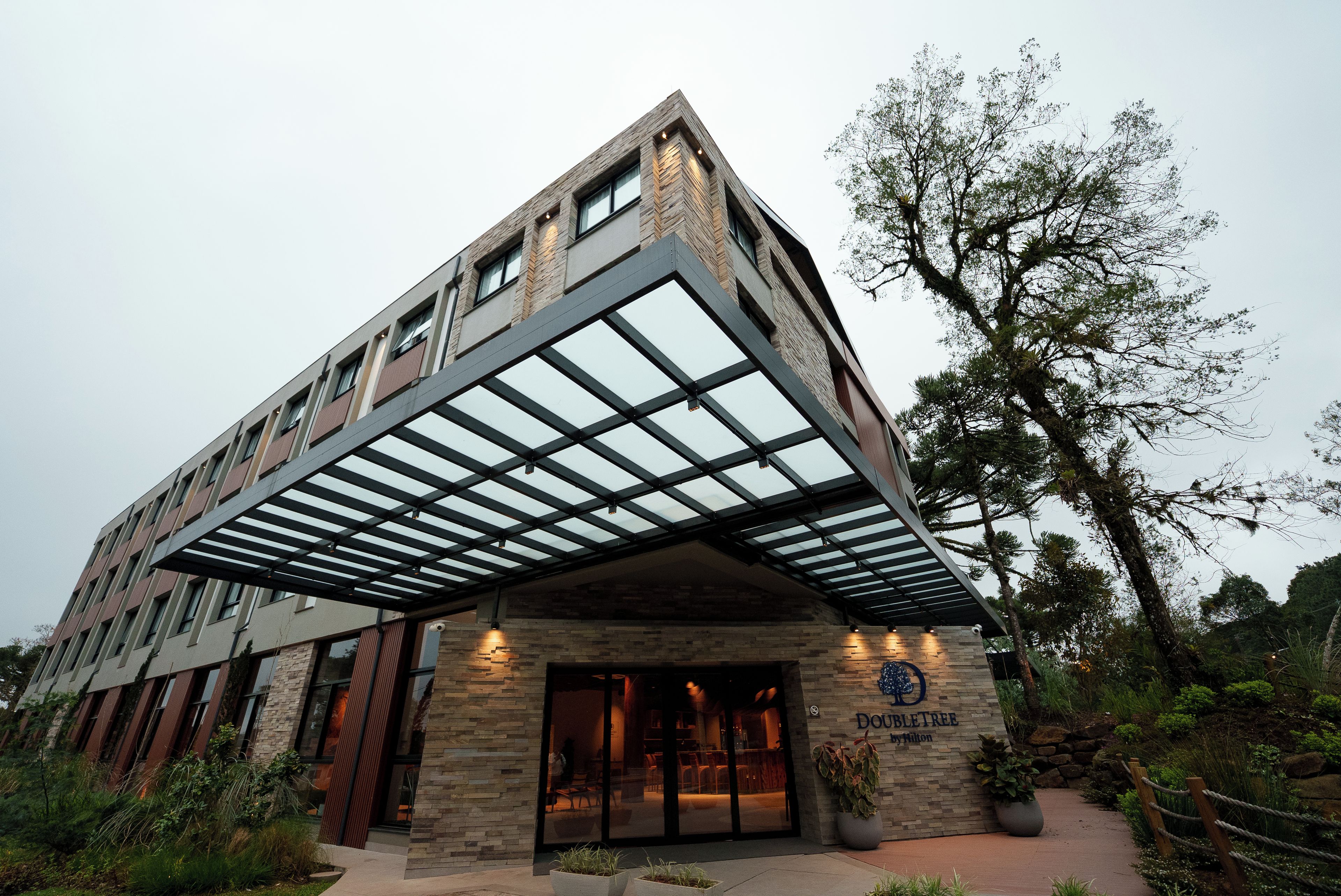 A modern building with a glass facade, a stone base, and a sign indicating it's a hotel.