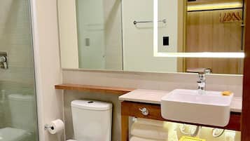 Une salle de bain moderne dotée d’une douche à parois de verre, de toilettes, d’un lavabo avec un meuble-vasque et d’un miroir avec éclairage intégré.