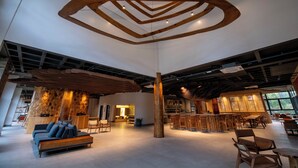 A spacious lobby with a modern wooden ceiling design, a seating area with sofas, and a bar with stools. - DoubleTree by Hilton Caracol Canela (Canela)