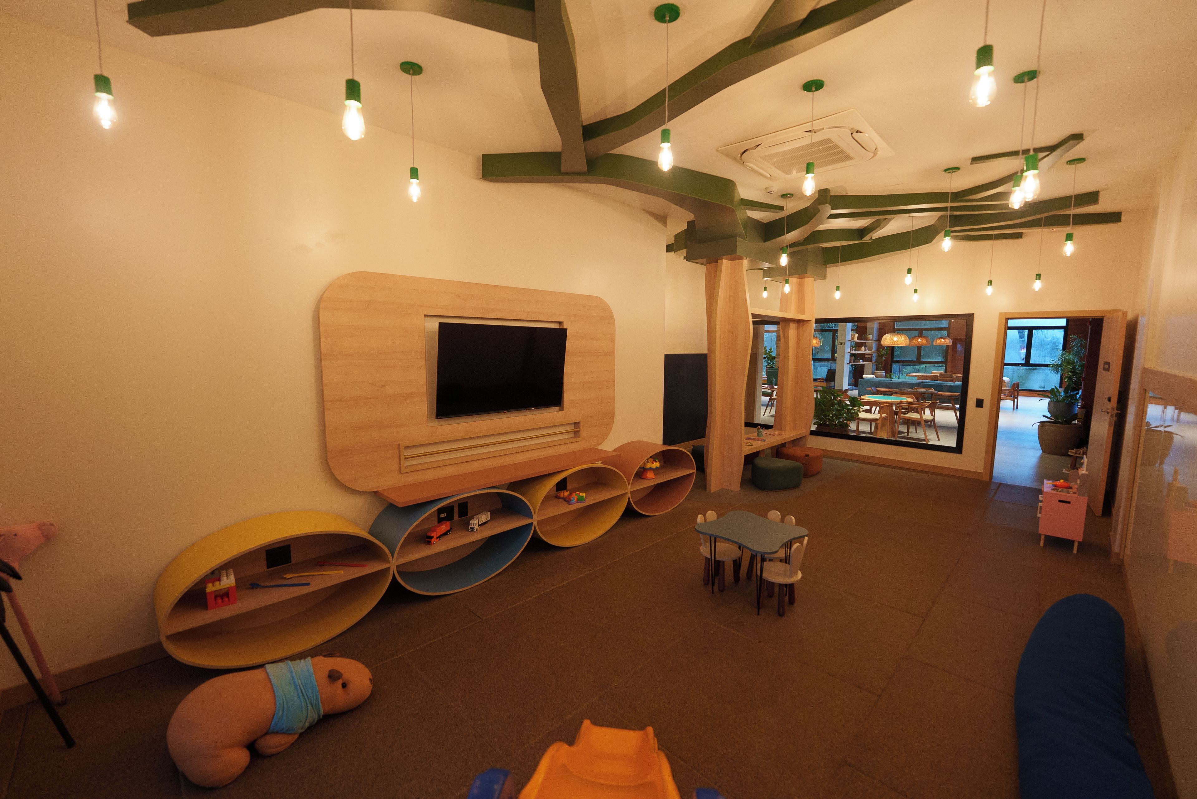 A children's play area with a television, circular seating, and a view into another room.