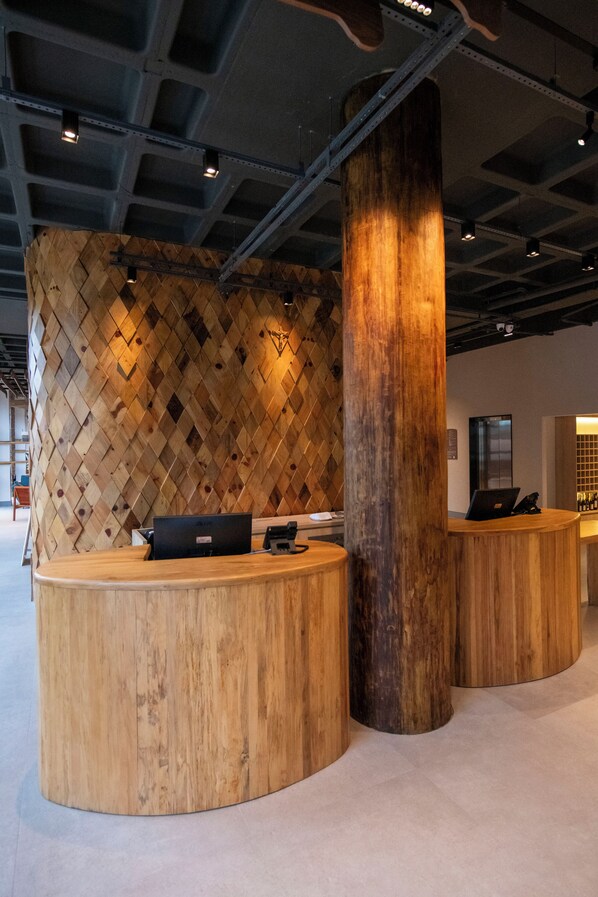 A reception area with wooden reception desks and a large wooden pillar.