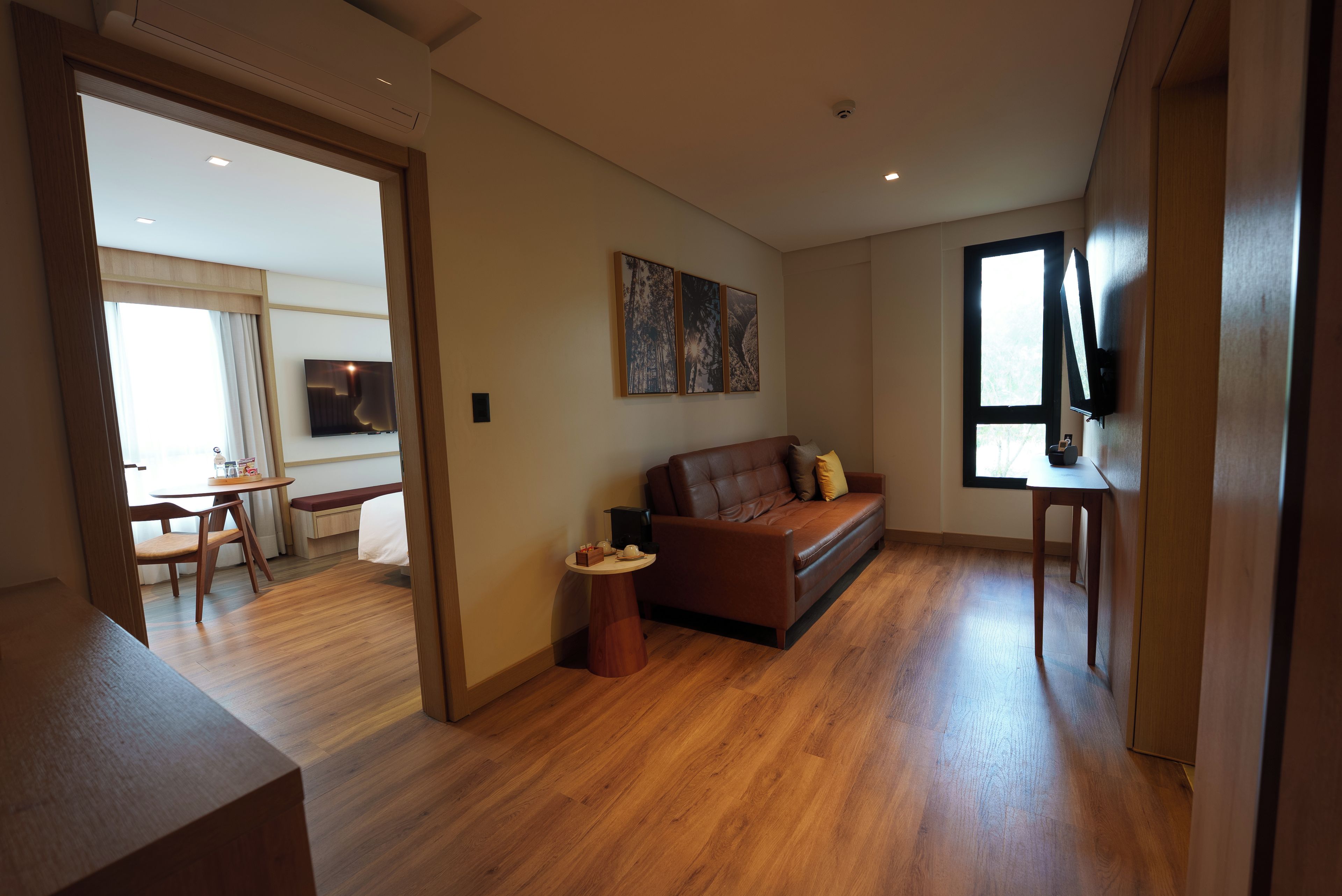 A modern living room with a brown leather sofa, a coffee table, and a flat-screen TV mounted on the wall.