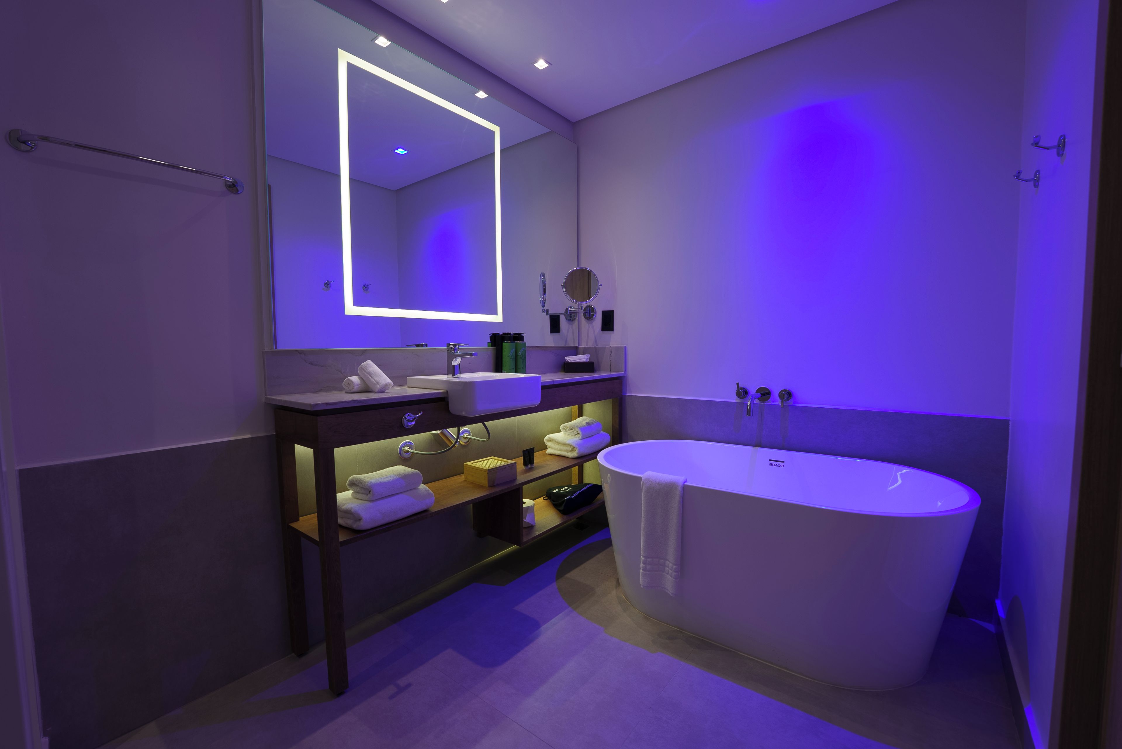 A modern bathroom with a freestanding bathtub, a vanity with a mirror, and a towel rack.