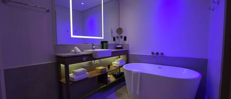 A modern bathroom with a freestanding bathtub, a vanity with a mirror, and a towel rack.