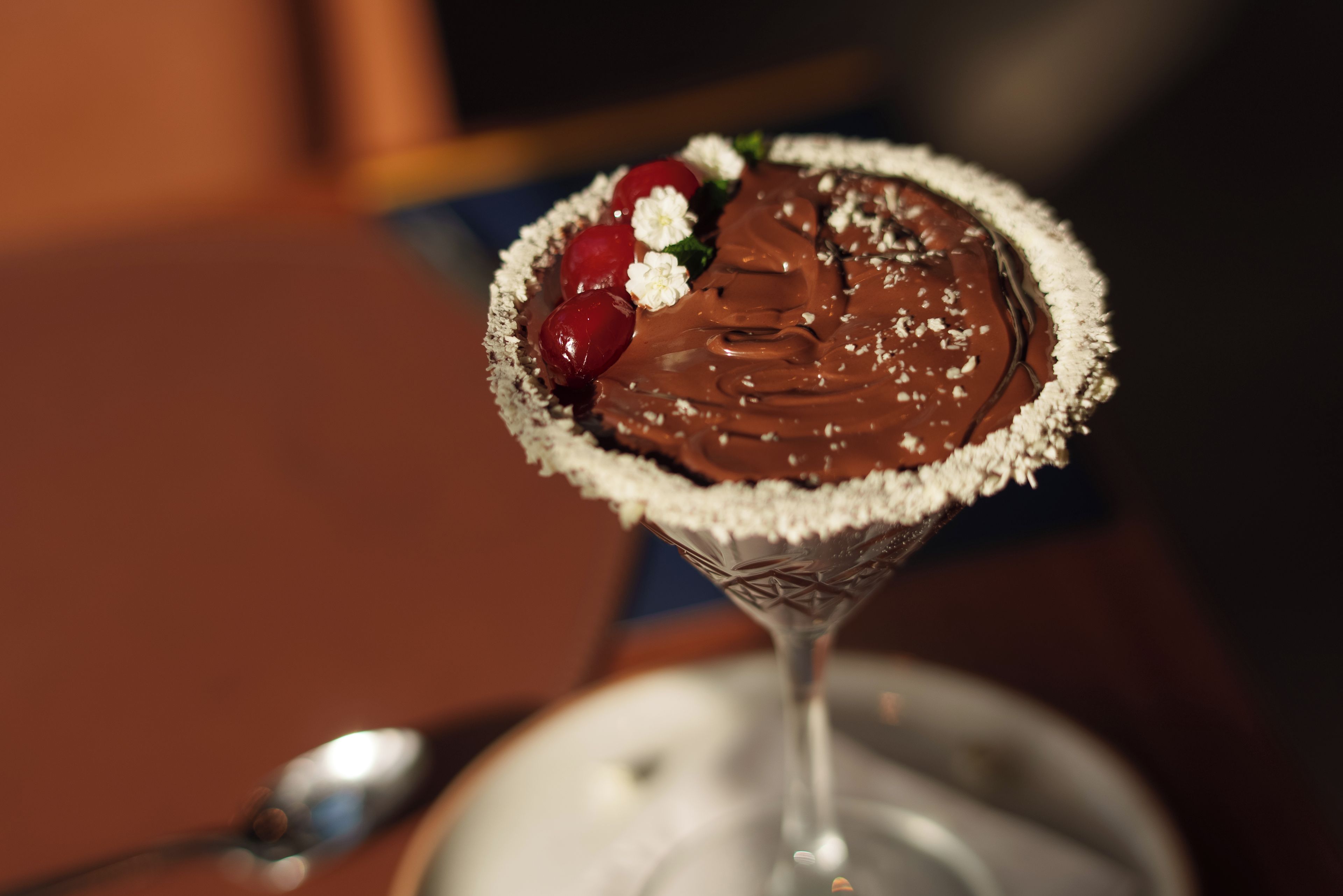 A dessert in a martini glass with a chocolate topping and garnishes.