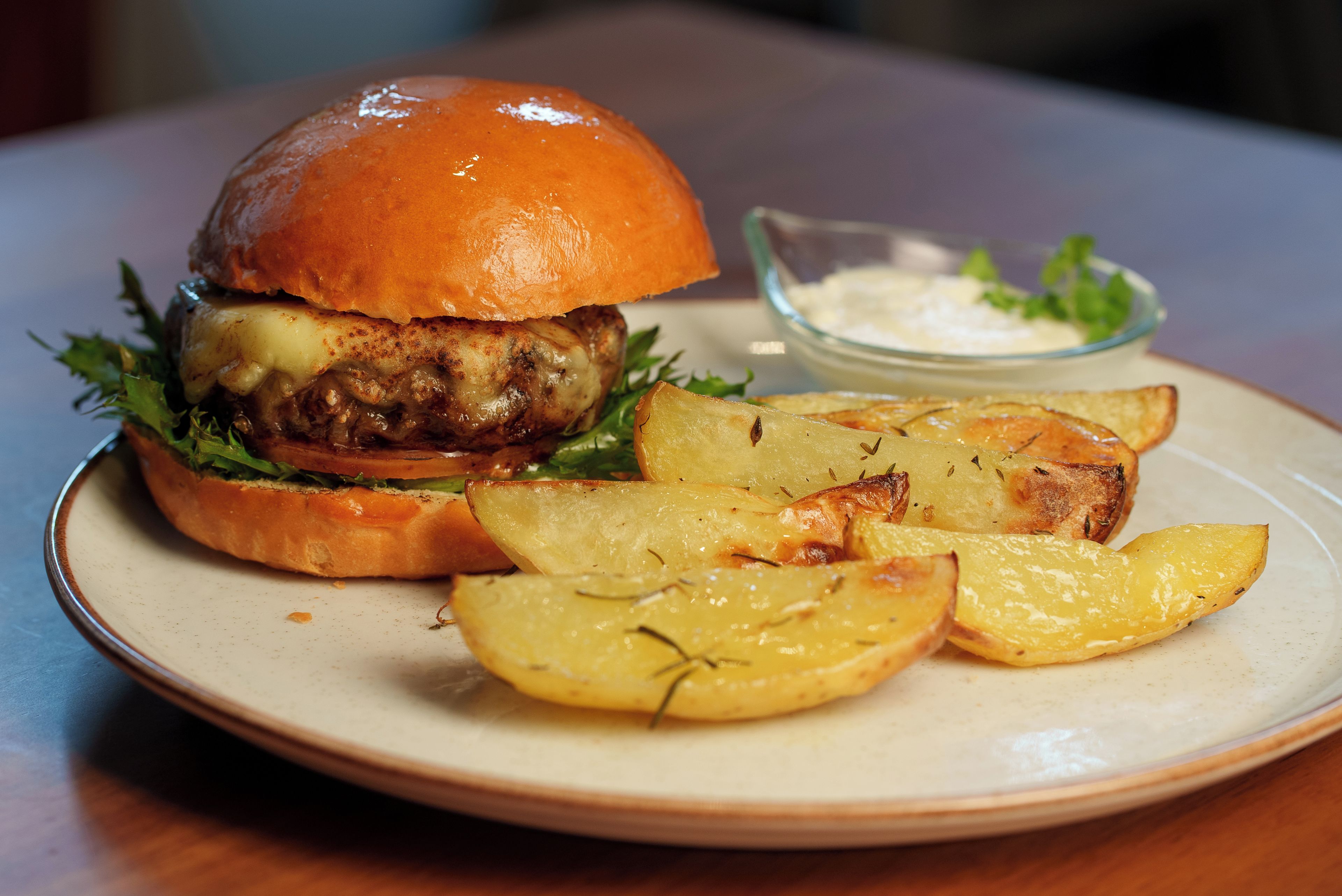 Ein Teller mit einem Burger, Pommes und einer kleinen Soßenportion.