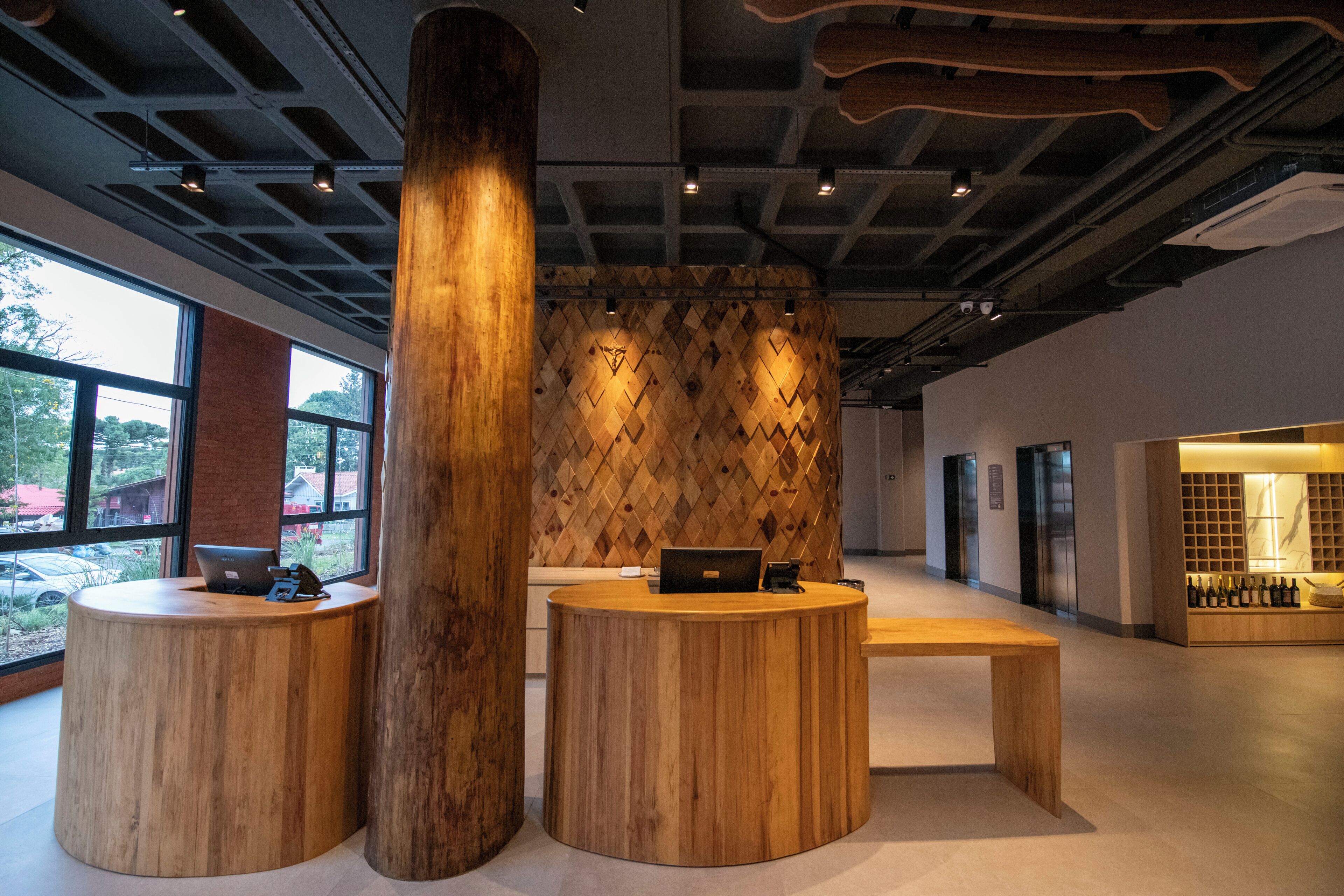 A reception area with wooden reception desks, a large wooden pillar, and a wall with a geometric pattern.