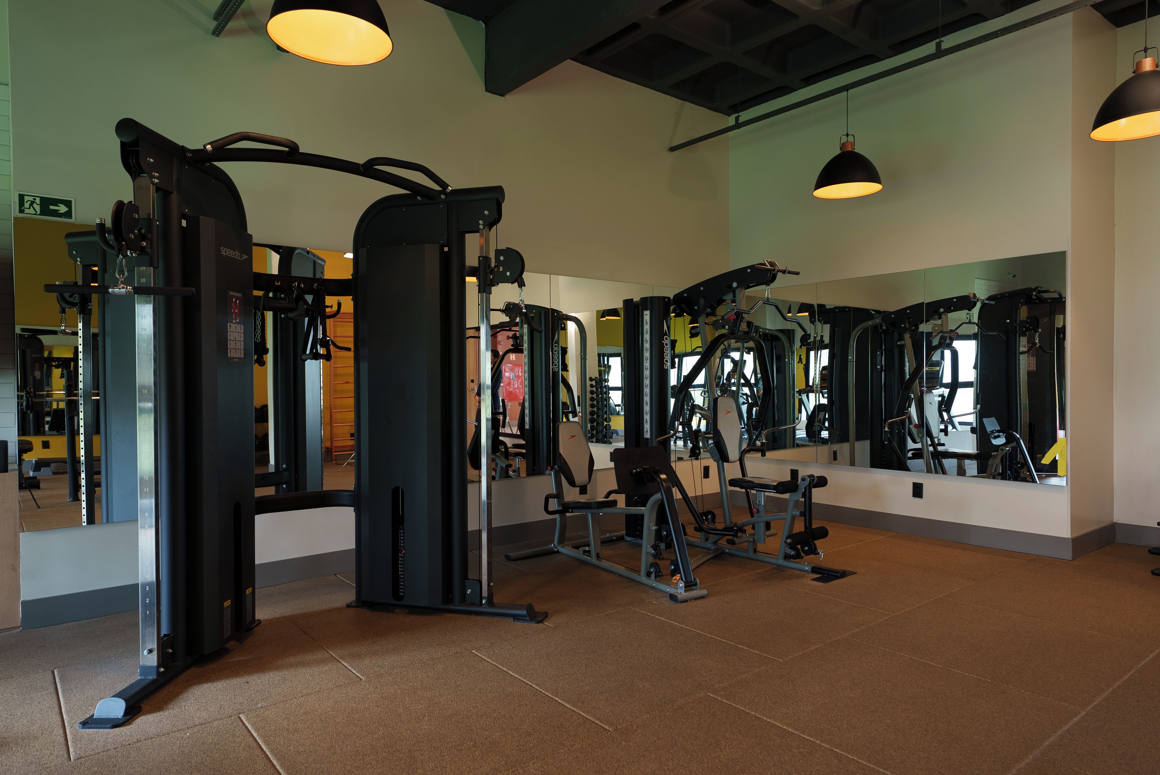 A gym with various exercise machines, mirrors, and a tiled floor.