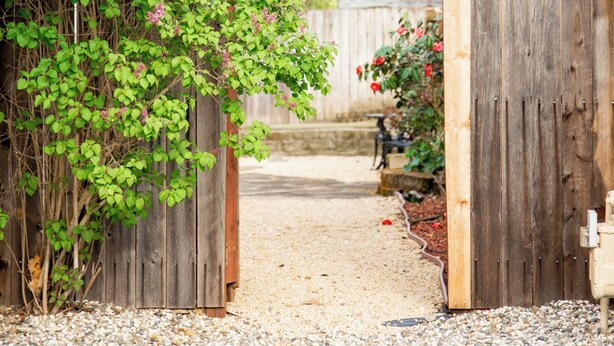 A gravel driveway leading to a wooden gate with a lattice design. - Parkside 4-bedroom house with complete fenced in yard in tranquil Santa Rosa. (Santa Rosa)