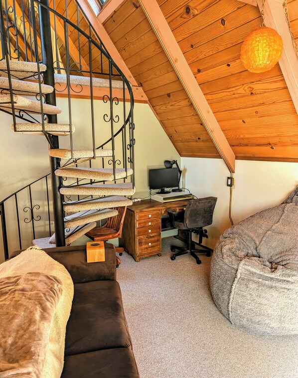 A cozy attic bedroom with a spiral staircase, a wooden desk, a computer, and a large bean bag. - Cozy & Charming Sierra Nevada mts cabin 40 minutes from Kirkwood Ski resort. (Pioneer)