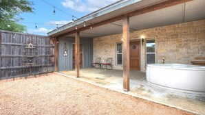A covered patio with stone walls, a hot tub, and outdoor seating. - Unit 2 - Bordeaux Gare Saint-jean (Fredericksburg)