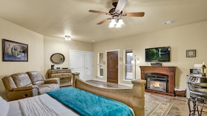 A bedroom with a bed, a ceiling fan, a fireplace, a television, and a leather armchair. - Unit 2 - Bordeaux Gare Saint-jean (Fredericksburg)