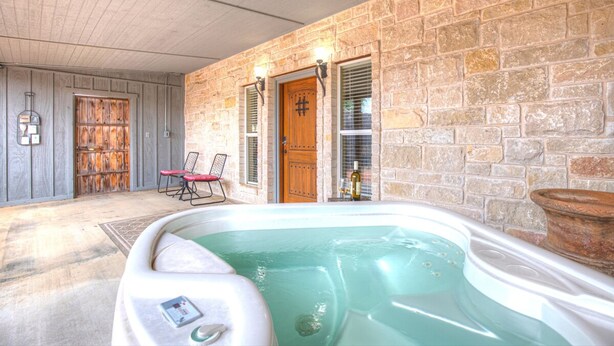 A spa area with a hot tub, stone walls, and a wooden door. - Unit 2 - Bordeaux Gare Saint-jean (Fredericksburg)