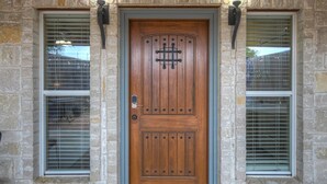 A wooden front door with a metal knocker, flanked by two windows with metal bars and a stone wall. - Unit 2 - Bordeaux Gare Saint-jean (Fredericksburg)