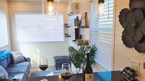 Une cuisine moderne avec des luminaires suspendus, une bouteille de vin, des verres, un canapé et un élément décoratif mural.