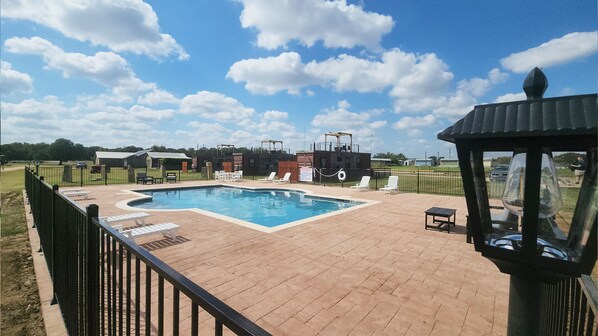 A rectangular swimming pool with a brick deck, surrounded by a black metal fence. - Unit 7 Napa Valley Station Stylish Stay (Fredericksburg)