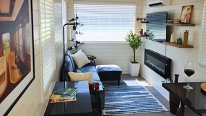 Ett mysigt vardagsrum med en soffa, ett soffbord, en tv och en krukväxt.