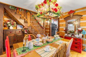 Un comedor acogedor con una escalera de madera, una araña y una decoración festiva en la mesa.