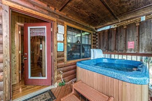 A wooden cabin with a hot tub, a red door, and a covered porch. - Smoky Mtn Lux Cabin Hot Tub Pool Views (Sevierville)
