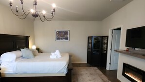 A bedroom with a bed, a chandelier, a fireplace, and a television. - Unit 1 Chianti Central Tuscan Wine Retreat (Fredericksburg)