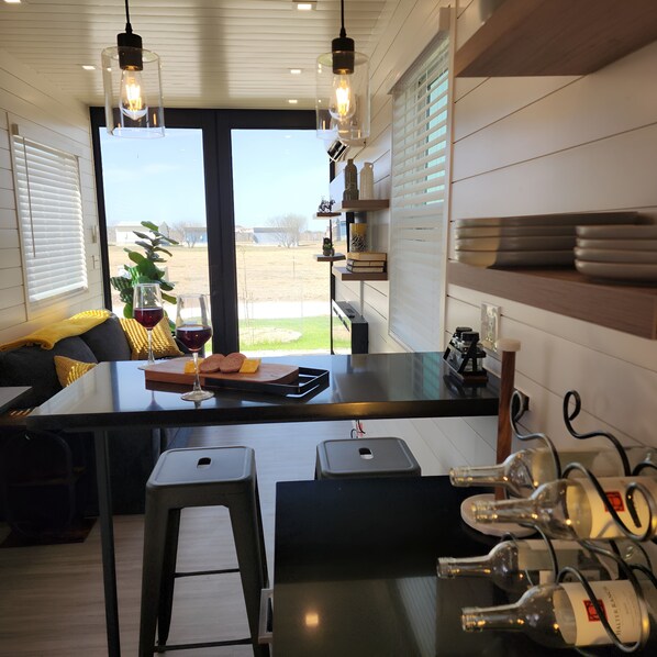 Una cocina moderna con una isla grande, taburetes de bar y una estantería para vinos.