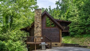A log cabin with a stone chimney, a deck, and a grill area. - Relaxing Eagles Ridge Getaway Hot Tub (Pigeon Forge)