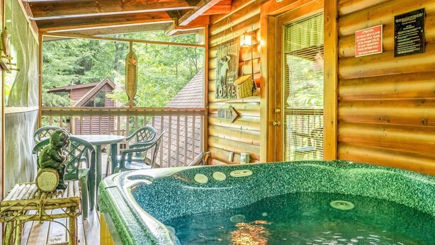 A wooden cabin with a hot tub, a porch with chairs, and a sign indicating 'Lodge'. - Relaxing Eagles Ridge Getaway Hot Tub (Pigeon Forge)