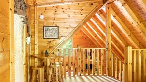 A wooden cabin interior with a high ceiling, a staircase, and a small table with stools. - Relaxing Eagles Ridge Getaway Hot Tub (Pigeon Forge)