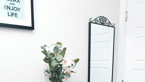 Una habitación con una consola de madera, un jarrón con flores, un espejo y una puerta.