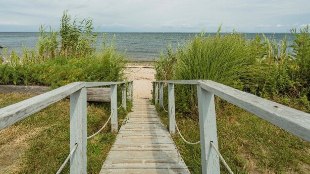 Un sentier en bois mène à une plage, et il est bordé de garde-corps des deux côtés.