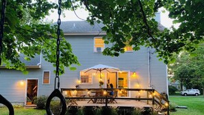 Une maison avec un porche, un espace salon extérieur et une balançoire.