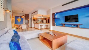 A modern living room with a sofa, coffee table, and a TV mounted on a blue accent wall.