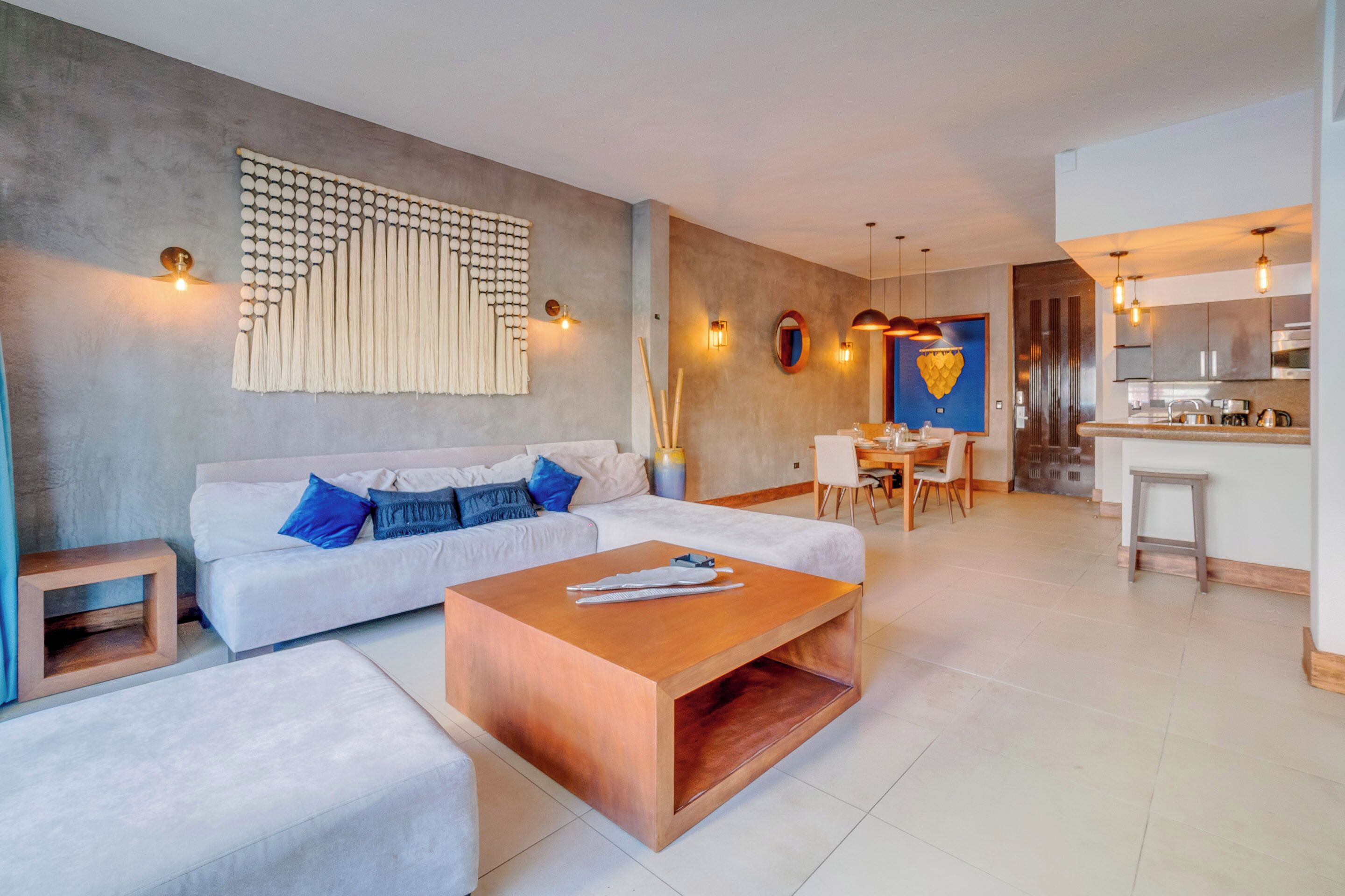 Ein modernes Wohnzimmer mit einem weißen Sofa, einem Holztisch und einer Essecke mit Tisch und Stühlen.
