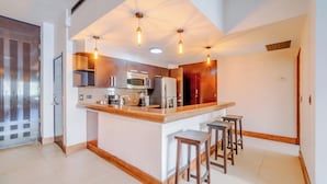 A modern kitchen with a central island, bar stools, and pendant lighting.